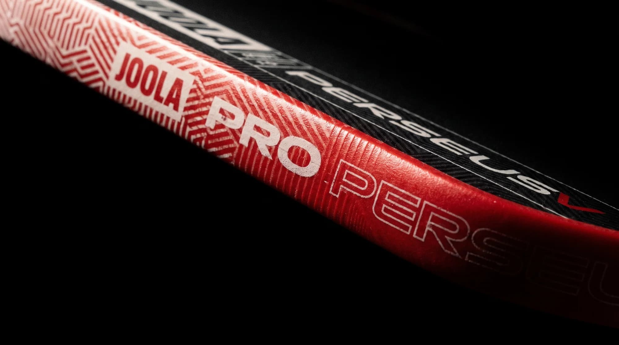 The red edge guard of a JOOLA Perseus Pro V in close-up, lit from above.